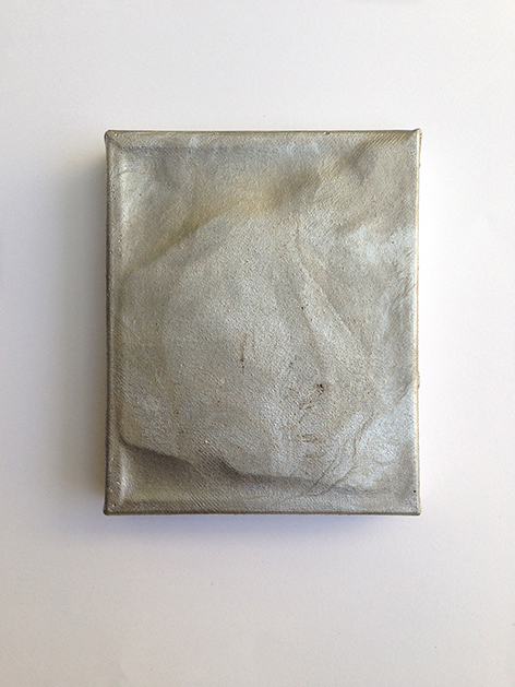 Eine verbeulte, silberne Leinwand, die an einer weißen Wand hängt